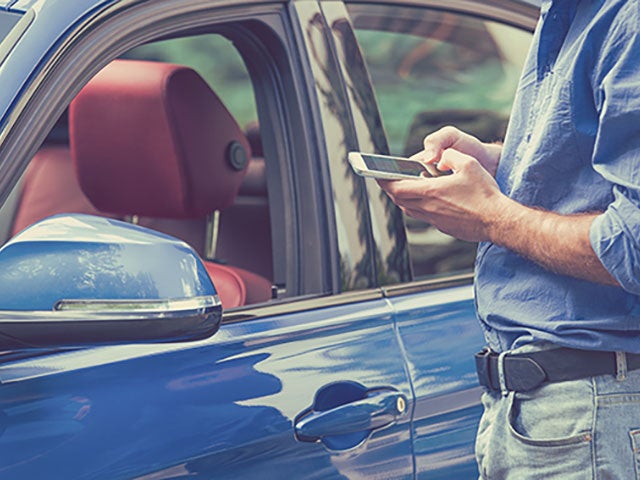 man on a phone next to car